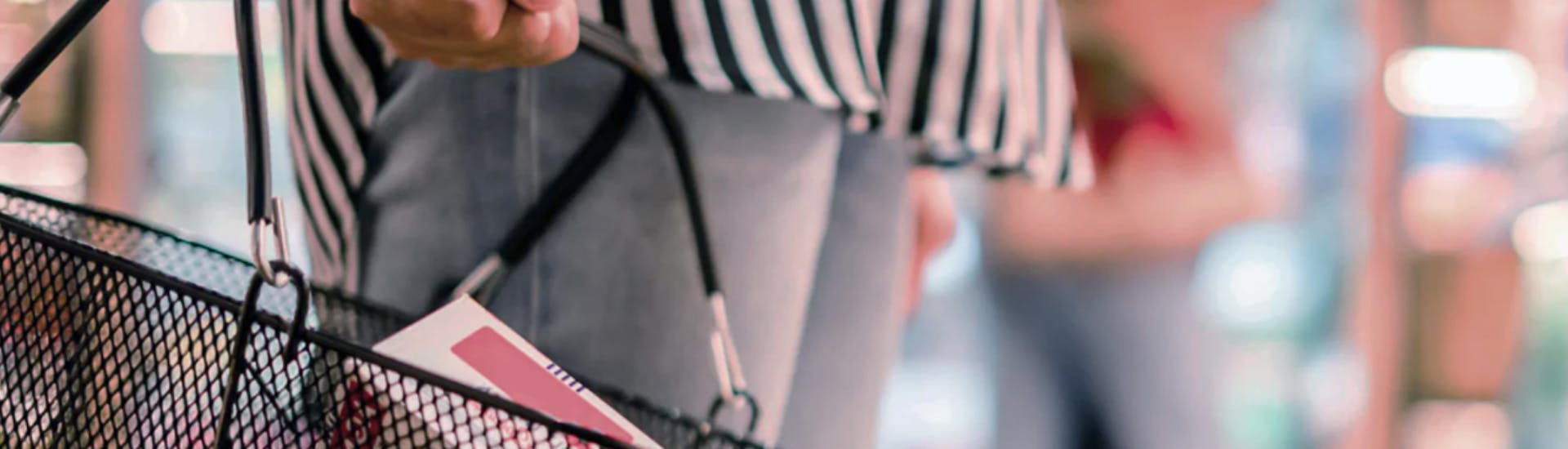Une femme tient un panier pour faire ses courses dans un supermarché